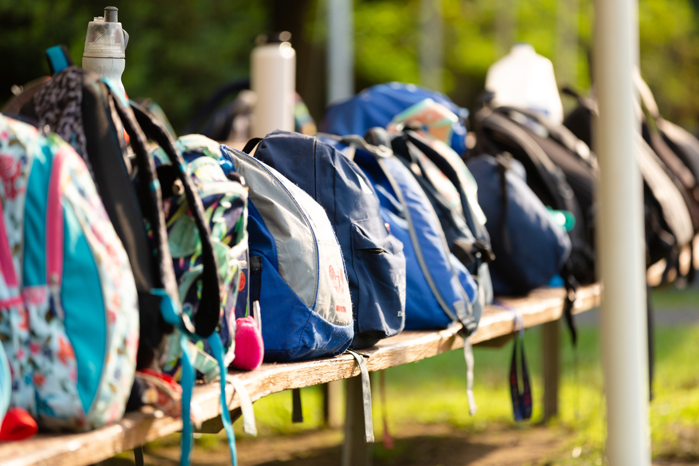 Backpacks lined up on a bench.