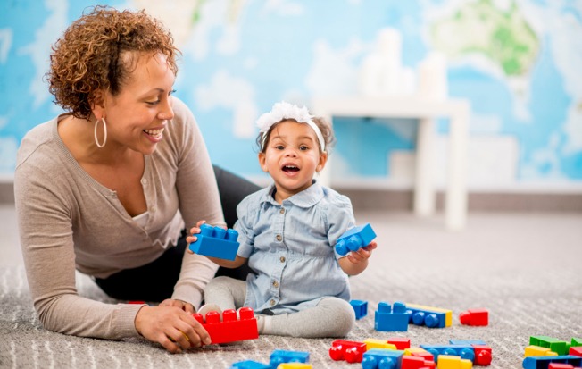 Teacher and infant playing with blocks.