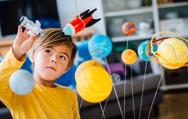 Young boy playing with a toy solar system.